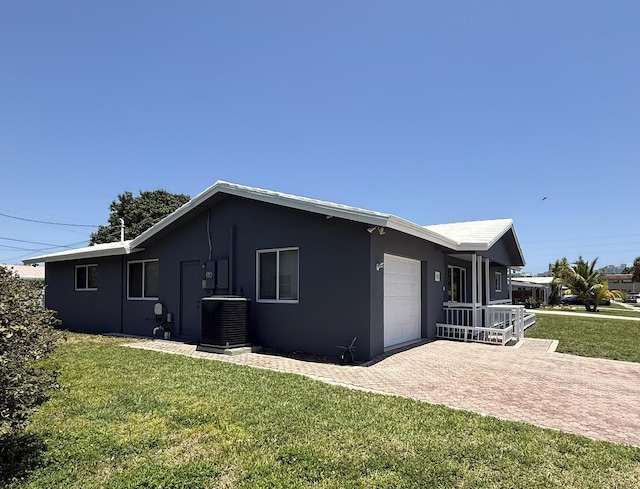 257 SW 5th St, Boca Raton, FL 33432 - view of property exterior with central AC, a garage, a lawn, and stucco siding