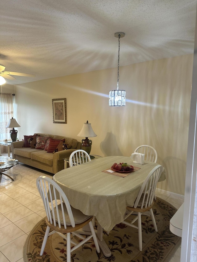 dining space featuring light tile patterned flooring, a chandelier, lofted ceiling, a ceiling fan, and a textured ceiling