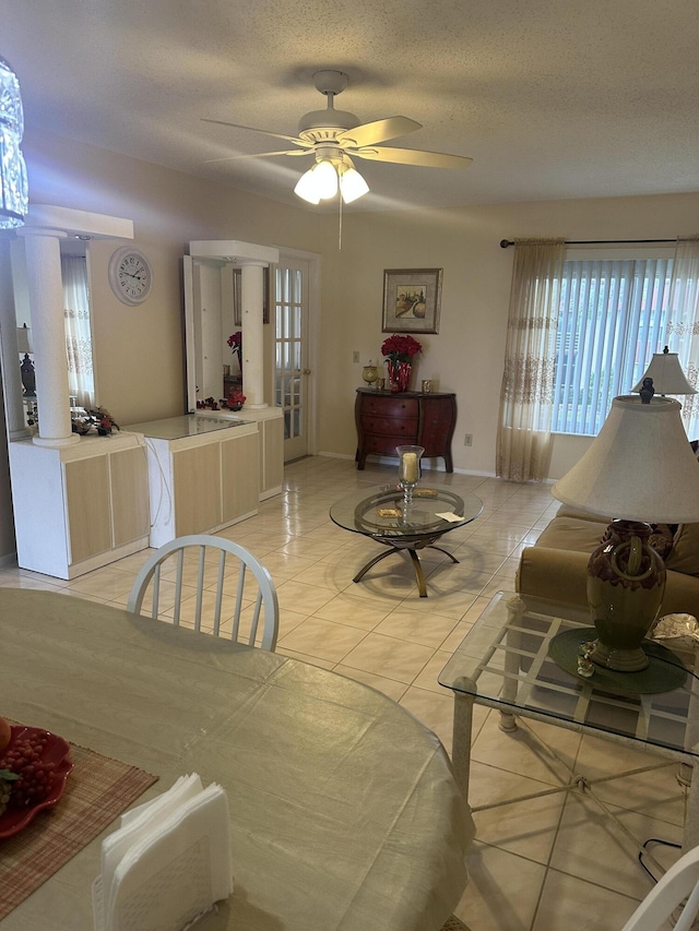 living room with ceiling fan, light tile patterned flooring, baseboards, and a textured ceiling