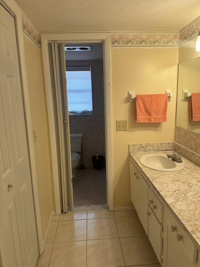 bathroom with a textured ceiling, toilet, tile patterned floors, and vanity