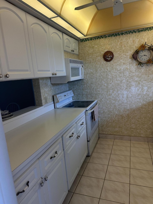 kitchen with white appliances, white cabinets, light countertops, and light tile patterned floors