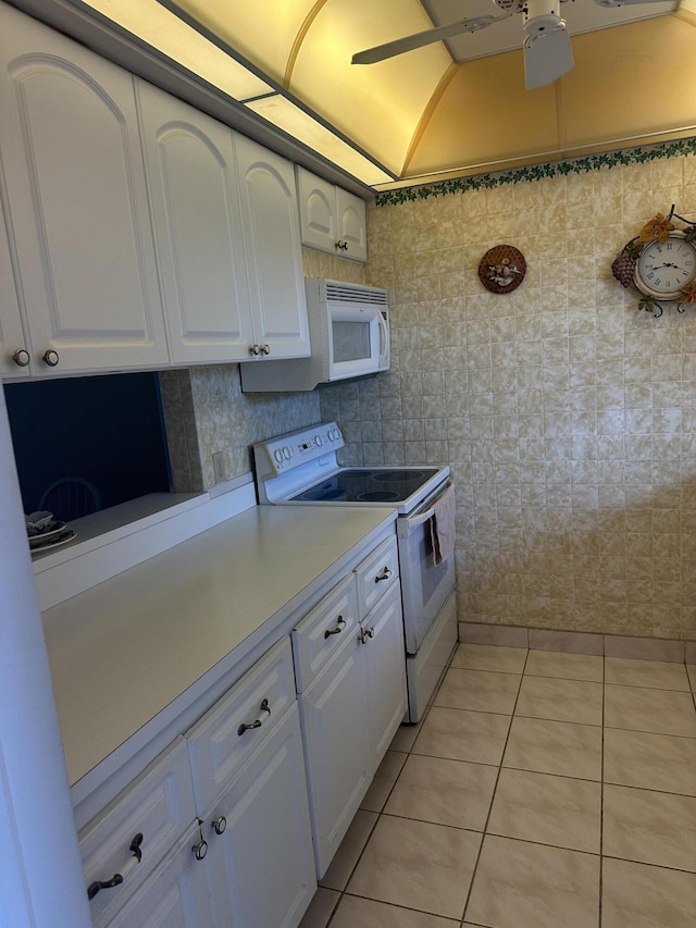 kitchen with white appliances, white cabinetry, light tile patterned floors, and light countertops