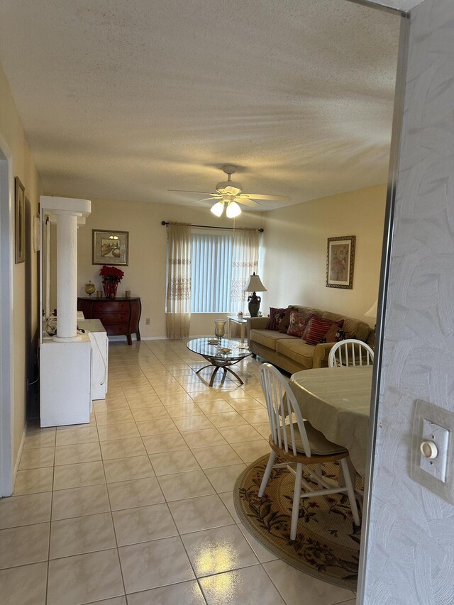 living room featuring a textured ceiling, light tile patterned flooring, ceiling fan, and baseboards