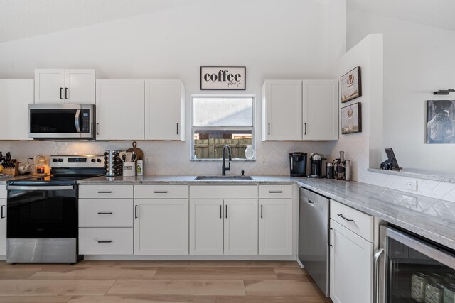 5157 Canal Cir S, Lake Worth, FL 33467 - kitchen featuring appliances with stainless steel finishes, a sink, vaulted ceiling, beverage cooler, and backsplash