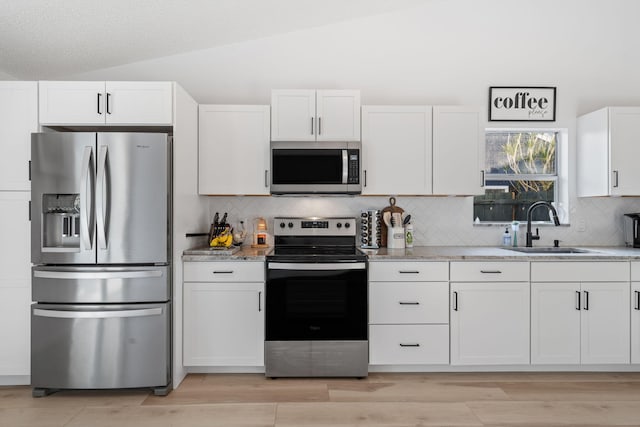 5157 Canal Cir S, Lake Worth, FL 33467 - kitchen with stainless steel appliances, a sink, vaulted ceiling, backsplash, and white cabinets