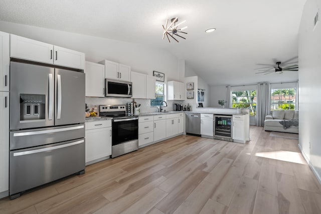 5157 Canal Cir S, Lake Worth, FL 33467 - kitchen featuring appliances with stainless steel finishes, wine cooler, lofted ceiling, white cabinetry, and light countertops