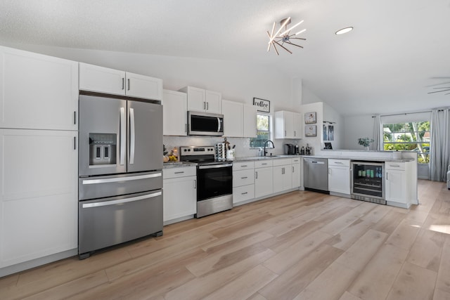 5157 Canal Cir S, Lake Worth, FL 33467 - kitchen featuring appliances with stainless steel finishes, wine cooler, a sink, white cabinetry, and high vaulted ceiling