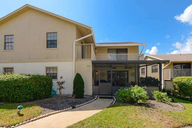 7427 SE Jamestown Ter, Hobe Sound, FL 33455 - view of front of home featuring a balcony, a ceiling fan, stucco siding, and a front lawn