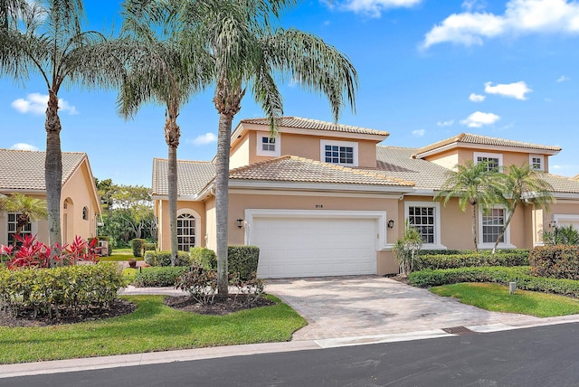 mediterranean / spanish-style home with a garage, stucco siding, driveway, and a tiled roof