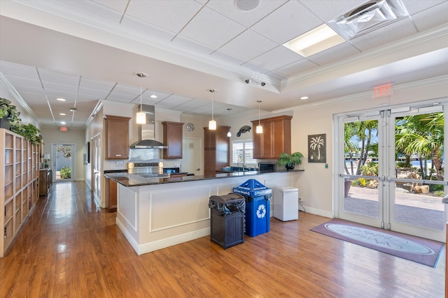 2016 S Federal Hwy Unit 206, Boynton Beach, FL 33435 - kitchen featuring wall chimney exhaust hood, french doors, wood finished floors, dark countertops, and brown cabinetry