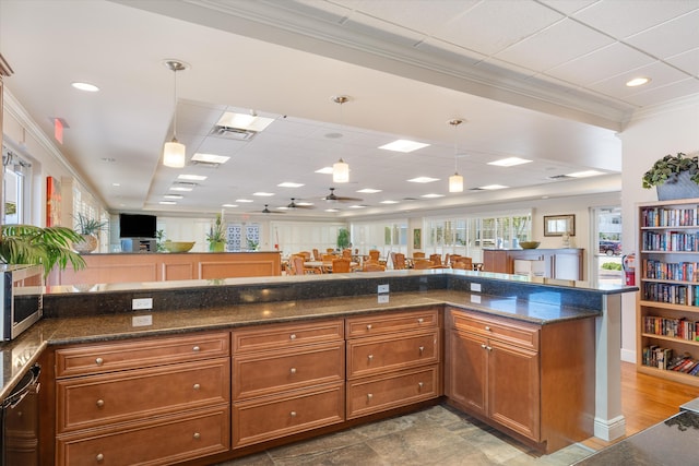 2016 S Federal Hwy Unit 206, Boynton Beach, FL 33435 - kitchen featuring stainless steel appliances, brown cabinetry, crown molding, a paneled ceiling, and hanging light fixtures