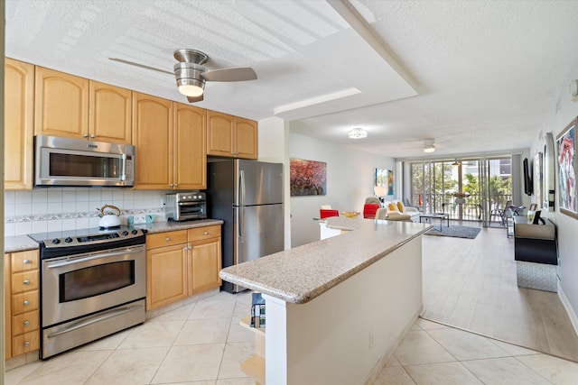 2016 S Federal Hwy Unit 206, Boynton Beach, FL 33435 - kitchen with appliances with stainless steel finishes, ceiling fan, open floor plan, a textured ceiling, and tasteful backsplash