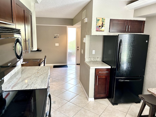 11231 Green Lake Dr Unit 104, Boynton Beach, FL 33437 - kitchen featuring freestanding refrigerator, light tile patterned floors, a textured ceiling, and dark brown cabinetry