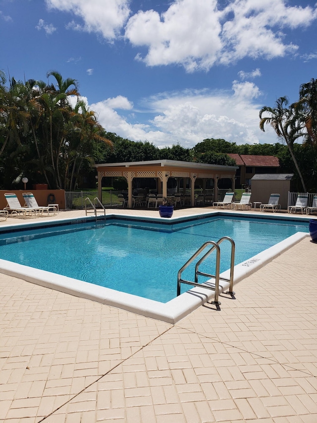 11231 Green Lake Dr Unit 104, Boynton Beach, FL 33437 - community pool featuring fence, a patio, a storage unit, and an outdoor structure