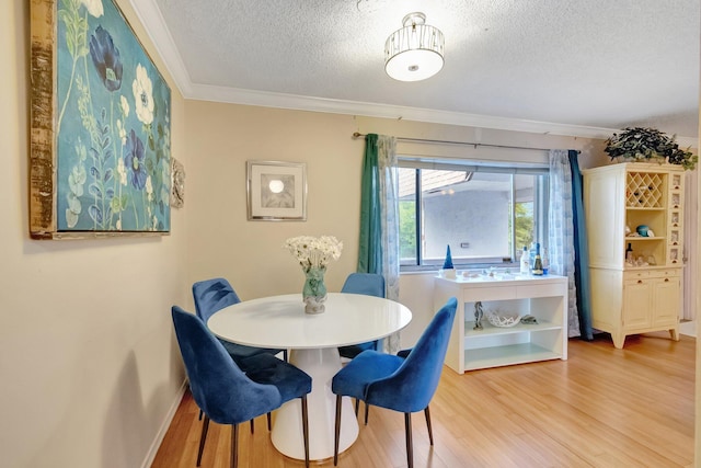 dining room featuring a textured ceiling, light wood-style flooring, ornamental molding, and baseboards