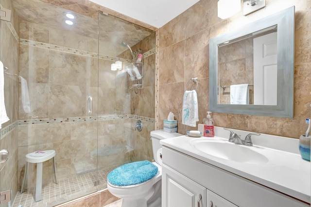 full bathroom featuring tile walls, toilet, a shower stall, and vanity