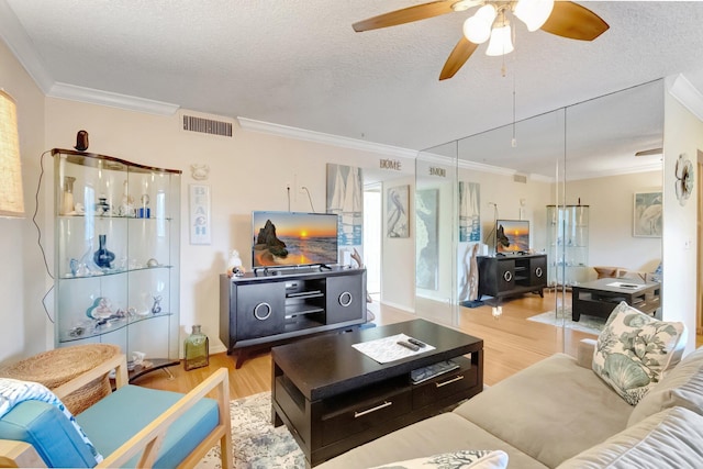living area with crown molding, wood finished floors, ceiling fan, and a textured ceiling