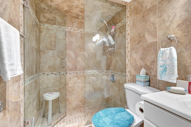 bathroom with tile walls, a stall shower, vanity, and toilet