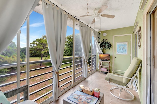 sunroom with a ceiling fan and tile patterned floors