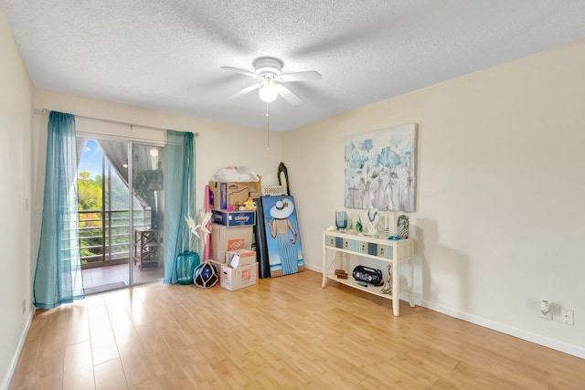 miscellaneous room featuring wood finished floors, a ceiling fan, a textured ceiling, and baseboards