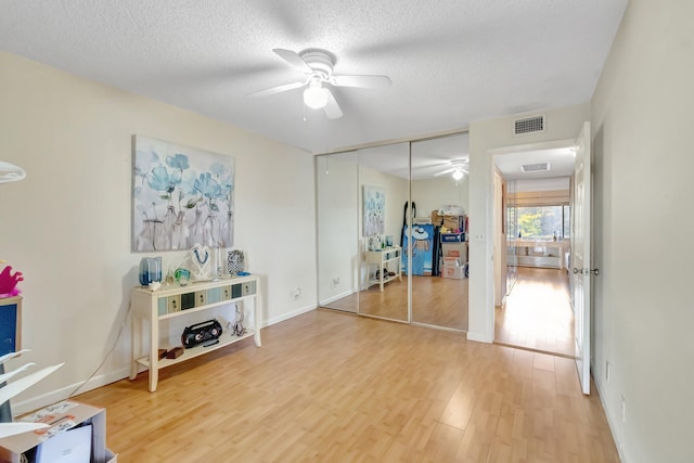 living area with ceiling fan, wood finished floors, a textured ceiling, and baseboards