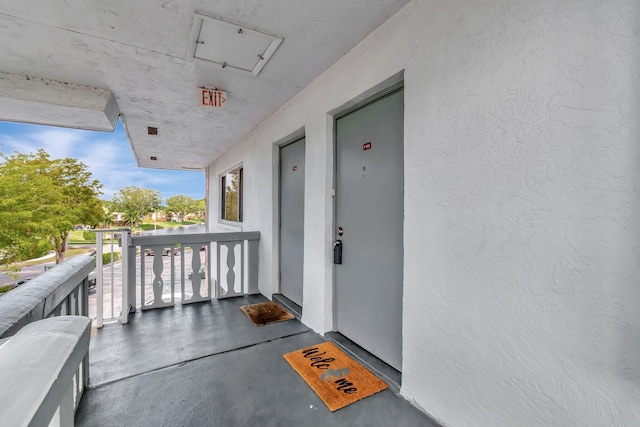 property entrance featuring stucco siding and a balcony