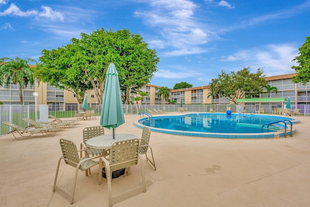 community pool with fence and a patio area
