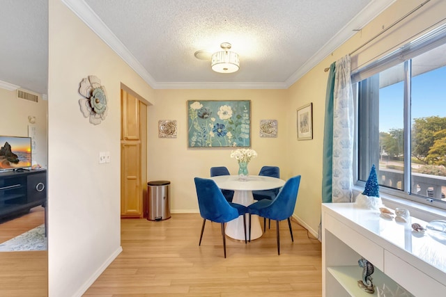 dining room featuring crown molding, light wood-style flooring, a textured ceiling, and baseboards