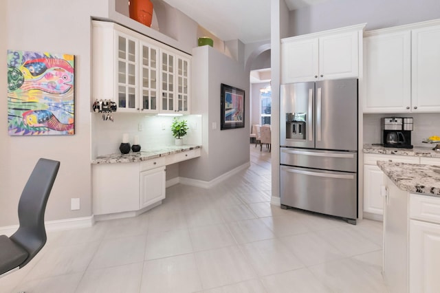 kitchen featuring stainless steel fridge with ice dispenser, backsplash, glass insert cabinets, and white cabinetry