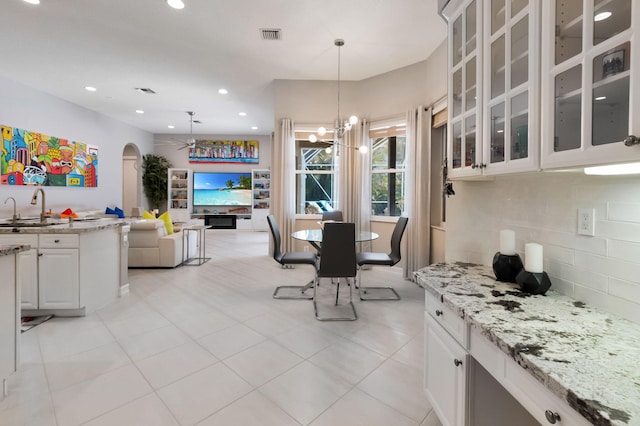 dining area with arched walkways, a chandelier, recessed lighting, and light tile patterned floors