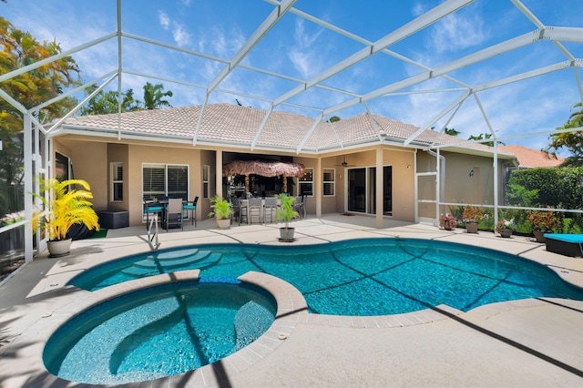 view of pool featuring a pool with connected hot tub, a patio, and glass enclosure