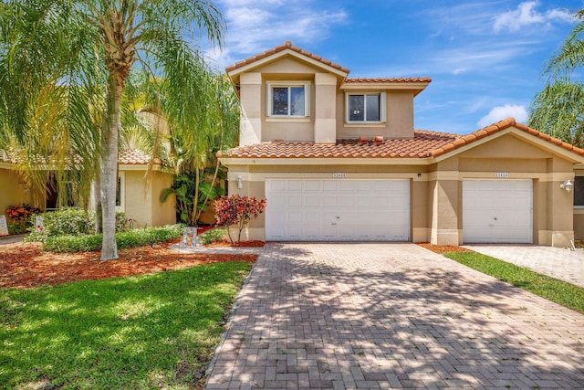 mediterranean / spanish house featuring stucco siding, a tile roof, and decorative driveway