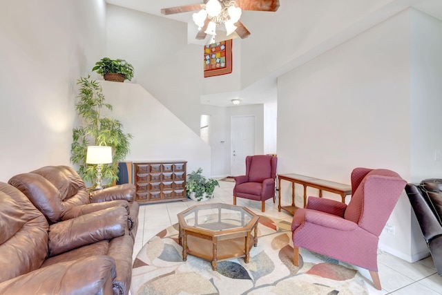 living room with tile patterned floors, a ceiling fan, a towering ceiling, and baseboards