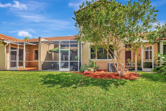 back of house featuring a yard, a tile roof, stucco siding, and cooling unit