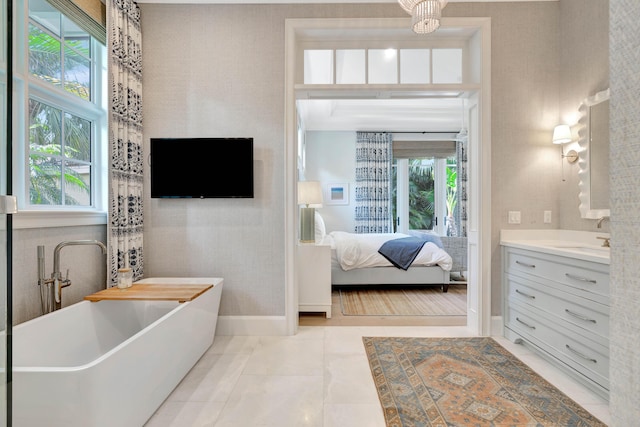 bathroom featuring vanity, a soaking tub, ensuite bathroom, and baseboards