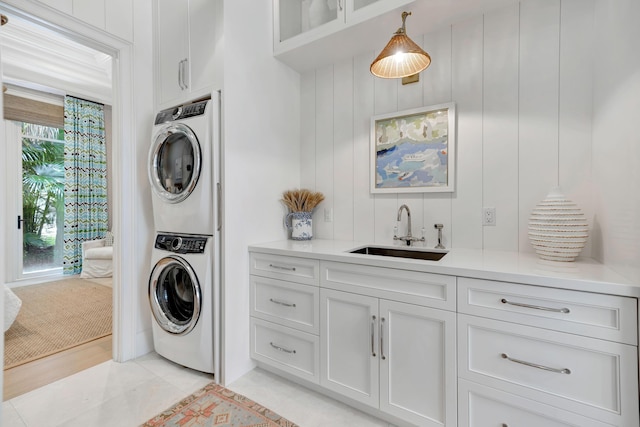 washroom with estacked washer and dryer, cabinet space, light tile patterned floors, and wet bar