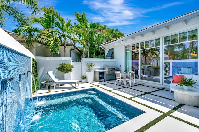 view of swimming pool featuring an outdoor kitchen, a patio, a fenced backyard, and area for grilling