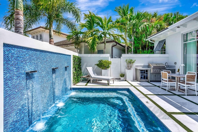 view of pool featuring exterior kitchen, area for grilling, a fenced backyard, and a patio