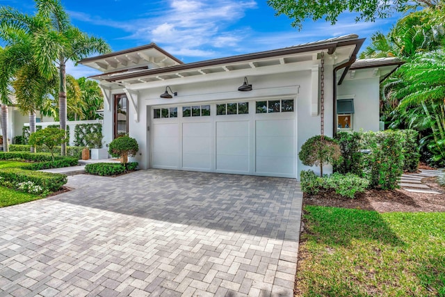 view of front of home with stucco siding, decorative driveway, and an attached garage