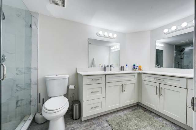 full bath featuring a marble finish shower, toilet, and vanity