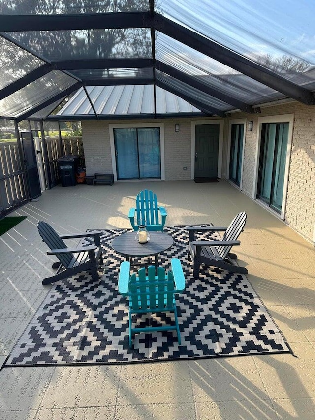 view of patio featuring glass enclosure and fence
