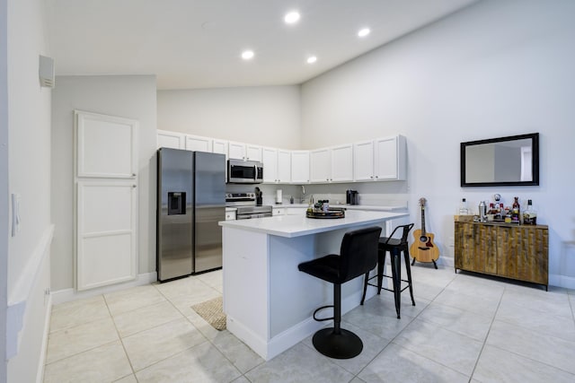 kitchen featuring appliances with stainless steel finishes, a breakfast bar, high vaulted ceiling, light countertops, and a kitchen island