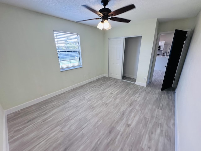 574 NW Marion Ave, Port Saint Lucie, FL 34983 - unfurnished bedroom featuring light wood finished floors, a textured ceiling, a closet, baseboards, and ceiling fan
