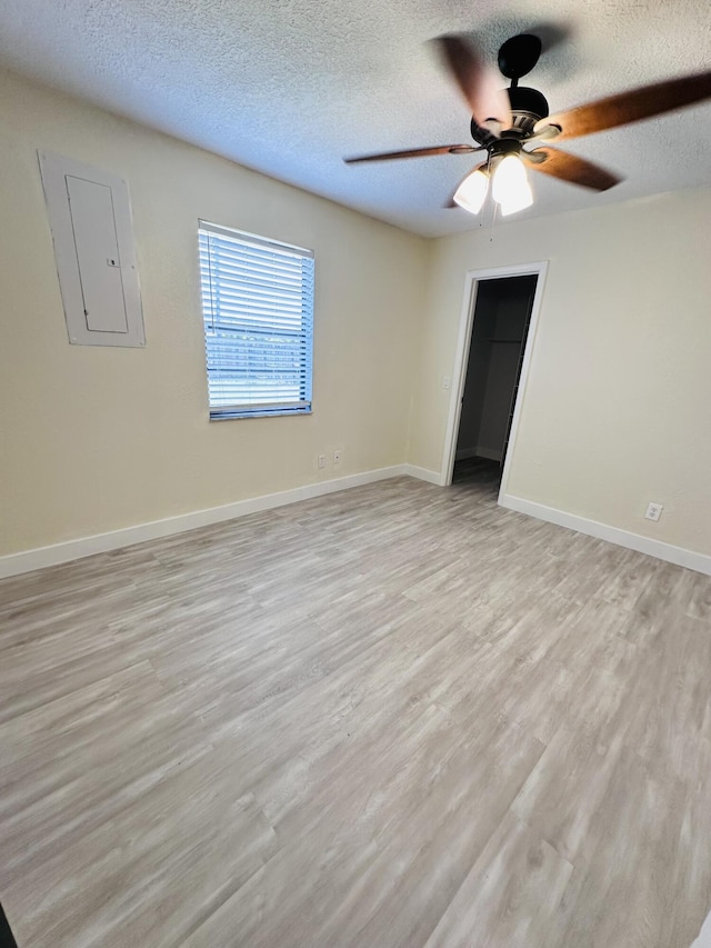 574 NW Marion Ave, Port Saint Lucie, FL 34983 - spare room featuring a ceiling fan, light wood-style floors, a textured ceiling, baseboards, and electric panel