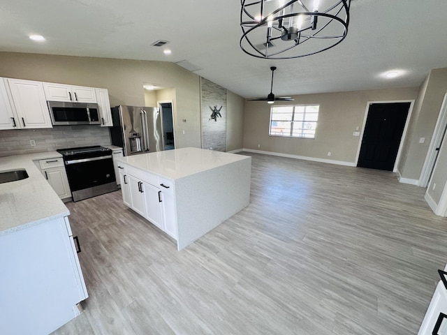 574 NW Marion Ave, Port Saint Lucie, FL 34983 - kitchen featuring stainless steel appliances, vaulted ceiling, a center island, a ceiling fan, and white cabinets