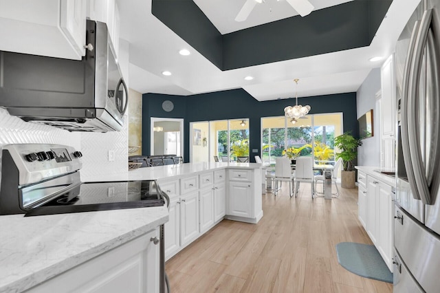 7816 Red River Rd, West Palm Beach, FL 33411 - kitchen with stainless steel appliances, white cabinets, recessed lighting, light wood-type flooring, and a peninsula