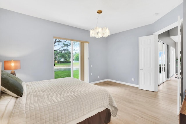7816 Red River Rd, West Palm Beach, FL 33411 - bedroom with a chandelier, light wood finished floors, baseboards, and access to outside