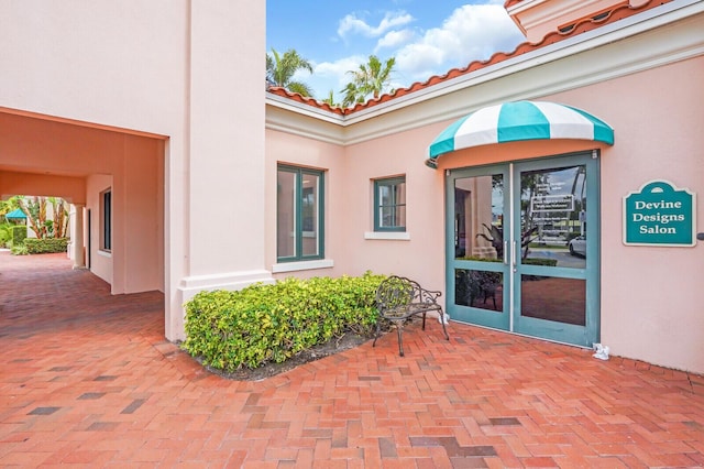7816 Red River Rd, West Palm Beach, FL 33411 - doorway to property featuring stucco siding, a tiled roof, and a patio