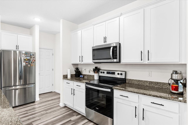 2509 SW Kenilworth St, Port Saint Lucie, FL 34953 - kitchen featuring appliances with stainless steel finishes, white cabinetry, light wood-style floors, dark stone counters, and recessed lighting