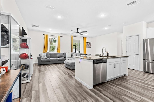 2509 SW Kenilworth St, Port Saint Lucie, FL 34953 - kitchen with appliances with stainless steel finishes, a sink, wood finished floors, white cabinetry, and a ceiling fan